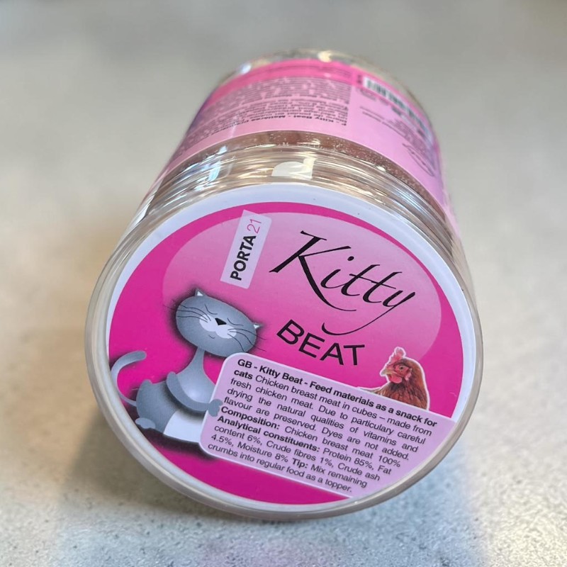 Transparent plastic container with a bright pink label, the words ‘Kitty Beat’ and a stylised grey cat. Visible inside: light-coloured, freeze-dried chicken breast cubes for cats, as stated.