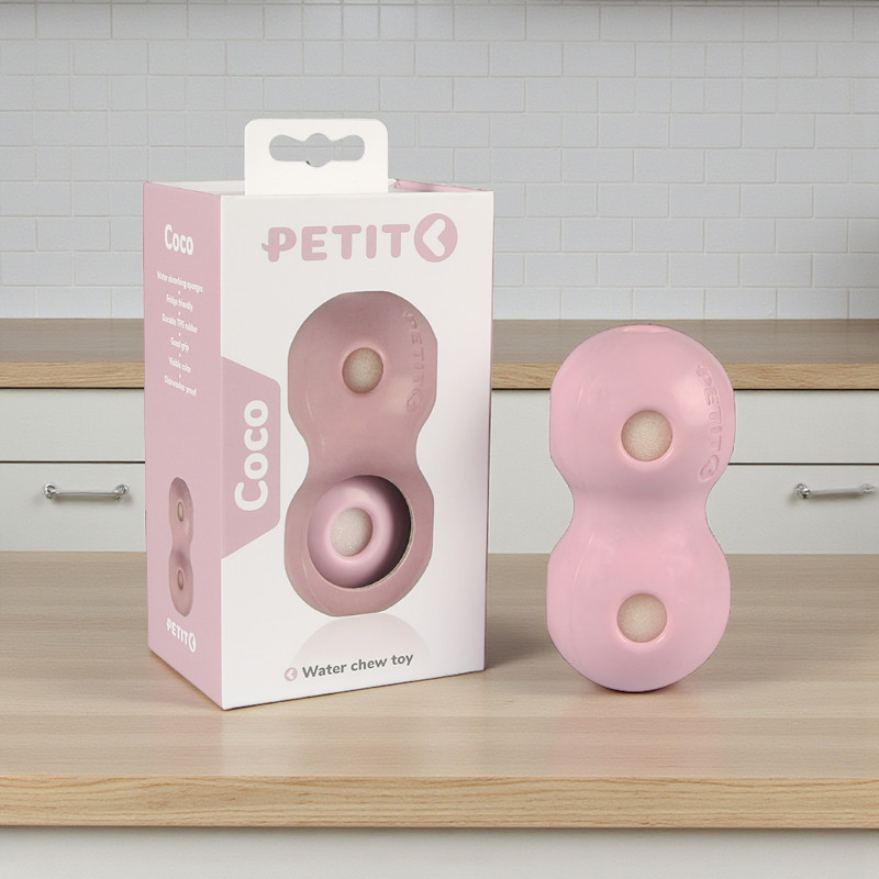 Pink dog toy "Coco" in figure of eight shape, with packaging in the background. Rubber.