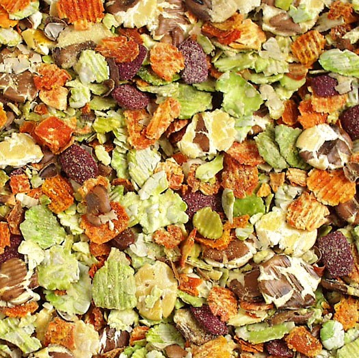 Nahaufnahme einer Mischung aus getrockneten Lebensmitteln: flache grüne Blättchen, geriffelte orange Chips, dunkle rotbraune Stücke und helle cremeweiße Körner. Texturen von glatt bis rau; wohl Gemüse und Getreide, ideal als Tierfutter.