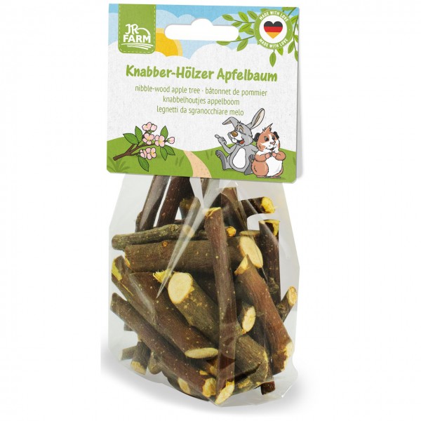 Durchsichtige Plastiktüte mit dunkelbraunen Knabberhölzern vom Apfelbaum für Kleintiere. Auf der Verpackung steht "JR FARM Knabber-Hölzer Apfelbaum" mit Illustrationen blühender Apfelzweige, Kaninchen und Meerschweinchen.