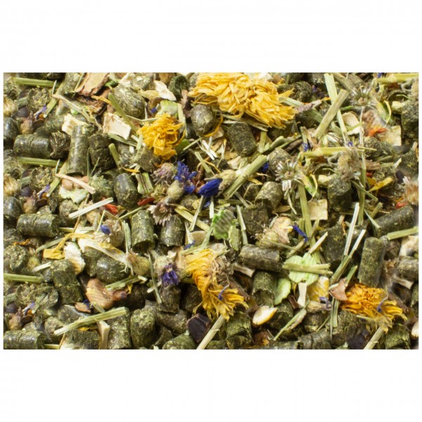 Detailed view of a mixture of dried ingredients: dark green pellets, light green blades of grass, bright yellow petals and purple flower fragments. Interspersed with brown and light-coloured plant fragments, suggesting animal feed or herbs.