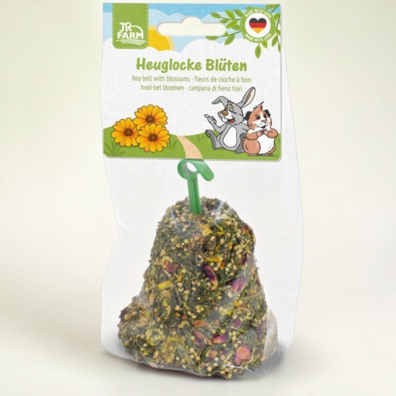 Glockenförmige Heuglocke für Kleintiere mit getrockneten Blüten und Samen, in transparentem Kunststoff verpackt. Oben ragt ein grüner Aufhänger heraus. Kartonverpackung von JR FARM mit "Heuglocke Blüten".