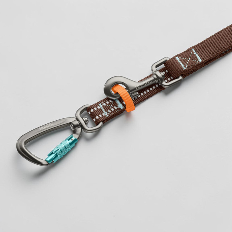 Detailansicht einer braunen HUNTER Action-Leine mit reflektierenden Punkten und hellblauen Akzenten. Mit robustem Aluminium-Sicherheitskarabiner mit hellblauem Schraubverschluss sowie zweitem Haken mit orangefarbenem Schnellverschluss.