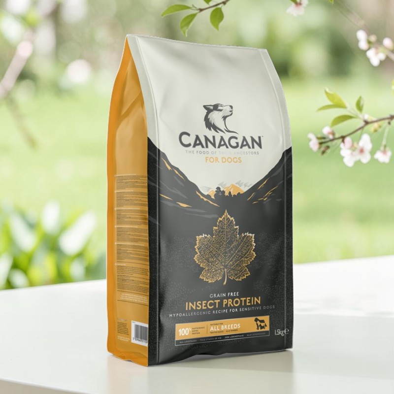 Canagan Aliments pour chiens sans céréales à base de protéines d'insectes : sachet gris foncé rehaussé de touches dorées, avec un motif de feuilles et de montagnes. Sur un fond vert clair flou orné de branches en fleurs.