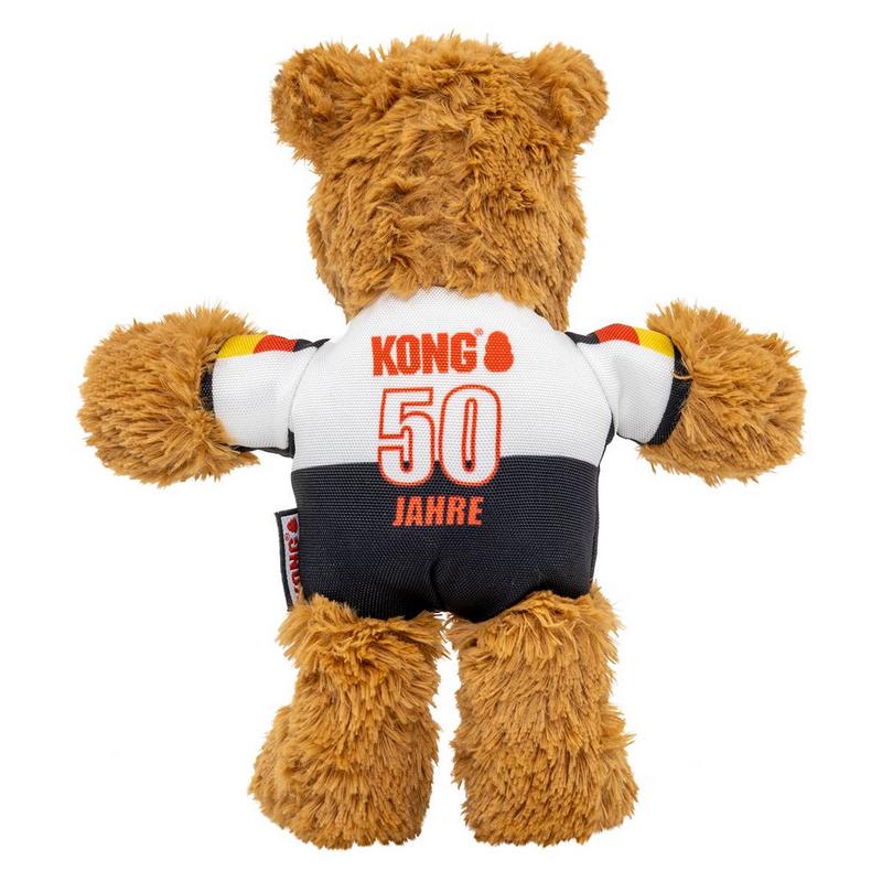 Un morbido orsacchiotto marrone, visto di spalle, indossa una maglietta a righe bianche e nere. Sulla parte bianca c'è la scritta "Kong" in maiuscolo rosso e sotto "50 ANNI". Le maniche sono decorate con nastri nei colori nero, rosso e giallo.