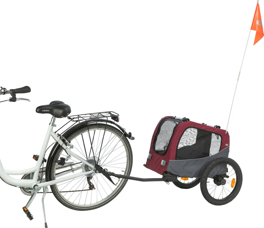Weißes Fahrrad mit schwarzem Sattel und Gepäckträger, am Hinterrad ein rot-grauer Haustieranhänger. Mit Netz-Seitenfenstern, zwei kleinen Rädern, langer Stange und leuchtend orangefarbener Sicherheitsflagge. Isoliert auf weißem Hintergrund.