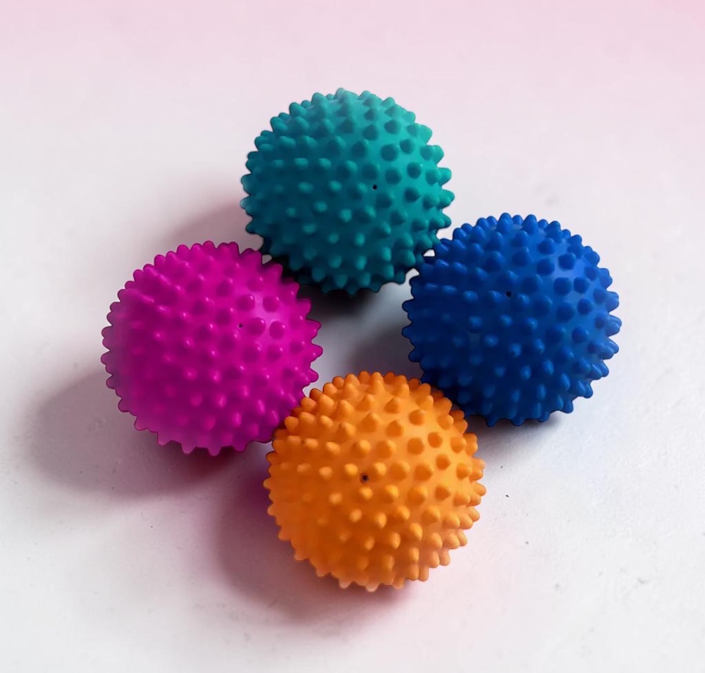 Vier bunte FitPAWS Paw Pods (türkis, magenta, blau, orange) auf heller Fläche: runde, genoppte Balance-Kissen, luftgefüllt, für Gleichgewichtstraining und Pfotenstimulation bei Hunden.