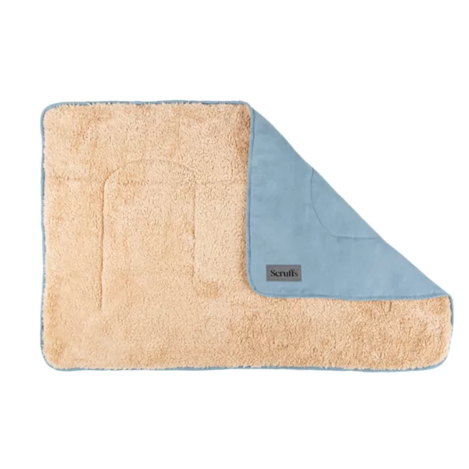 Couverture beige pour chiens avec surface moelleuse et coin bleu rabattu, étiquette visible.