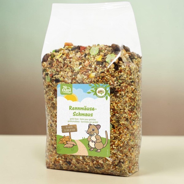 Sachet transparent « JR Farm Festin pour gerbilles » : mélange de graines, céréales, légumes séchés et granulés. Étiquette avec gerbille dessinée, ciel ensoleillé, mentions « 38 variétés » et « aliment complet ».