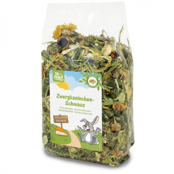 Transparent bag containing JR Farm Dwarf Rabbit Treat: a rich mix of dried grasses, herbs, flowers such as marigolds, and pellets for dwarf rabbits. Label featuring cartoon rabbits and carrots; 100% natural.