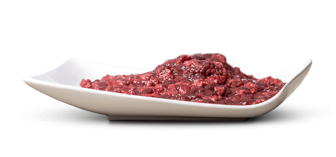 Weiße, geschwungene Servierschale mit dunkelroter, feuchter Masse aus kleinen, unregelmäßigen Fleischstücken in dickflüssiger Sauce, erinnert an hochwertiges Feuchtfutter oder reichhaltige Pastete; Oberfläche glänzt leicht.