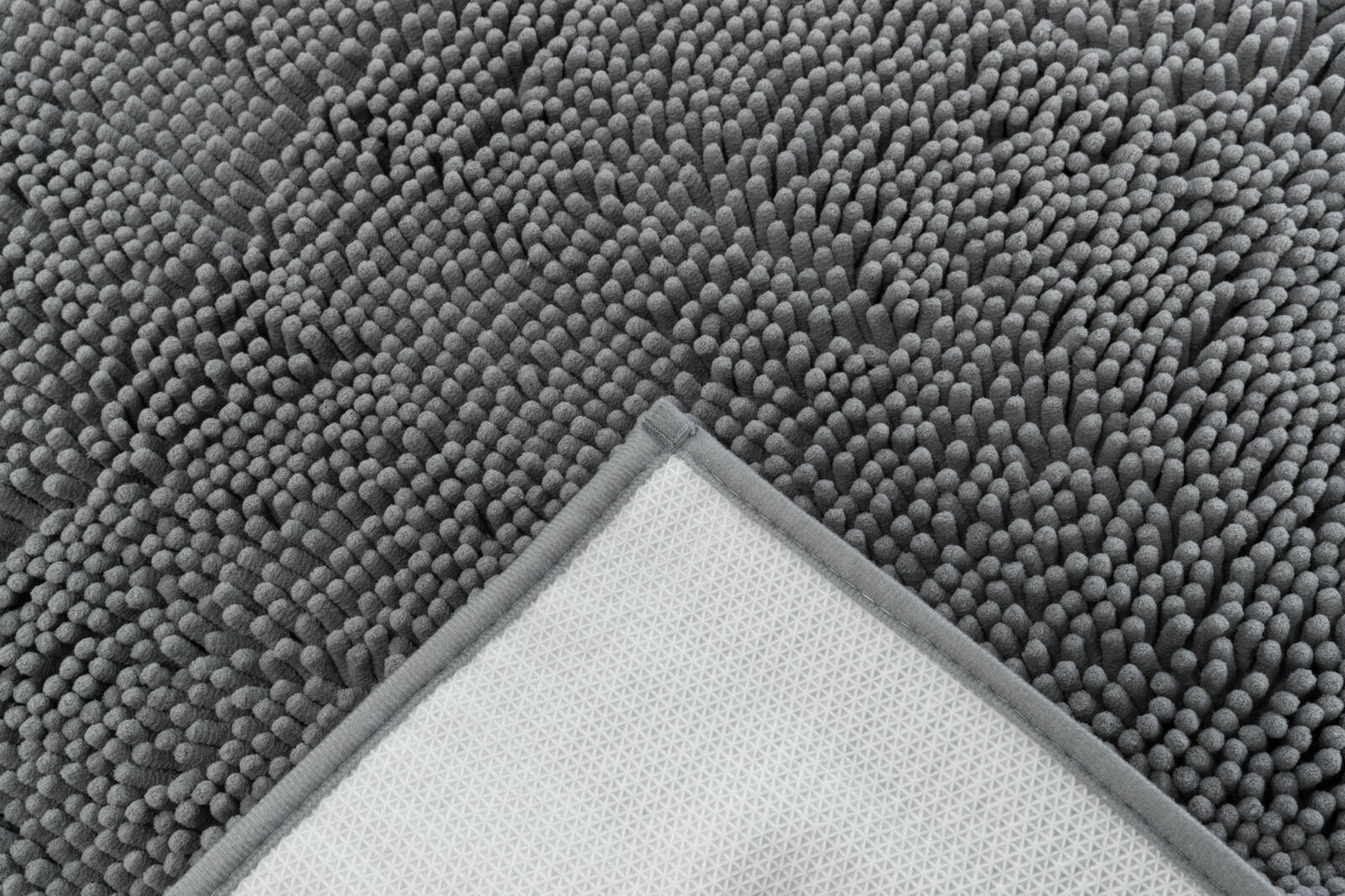 Grey, long-pile dirt-trapping mat with raised dots; the folded-over corner reveals a grey edge and a white, non-slip honeycomb underside. Absorbs dirt and moisture.