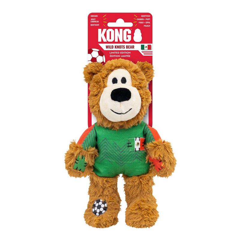 Orsacchiotto di peluche marrone con maglia da calcio verde, maniche arancioni e toppa con bandiera del Messico. Zampe con toppe colorate, pallone da calcio sul piede. Sorridente, in confezione rossa Kong WILD KNOTS.