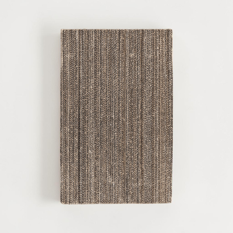Rectangular block of vertically cut corrugated cardboard. Surface shows fine parallel vertical lines revealing the corrugation. Natural brown and beige tones with shadowed grooves, against a white background.