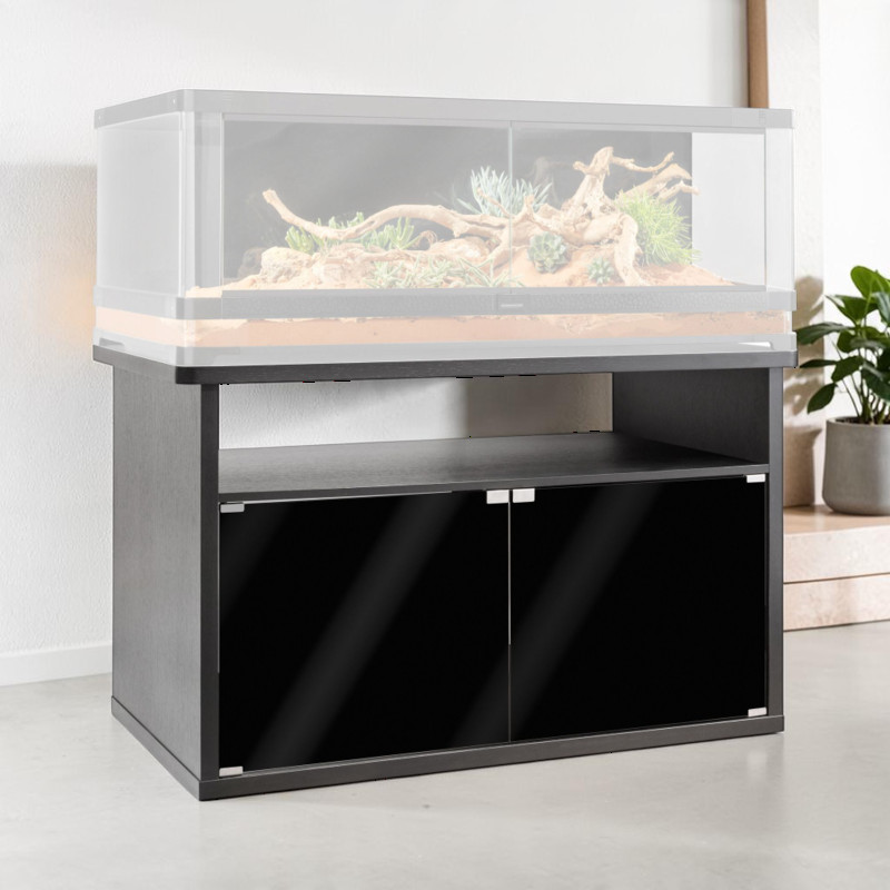 Meuble bas moderne et robuste « Exo Terra Vista 120 » anthracite foncé dans une pièce lumineuse. Avec deux portes avant noires brillantes et un rangement pour accessoires et matériel du terrarium. Grand terrarium transparent dessus.