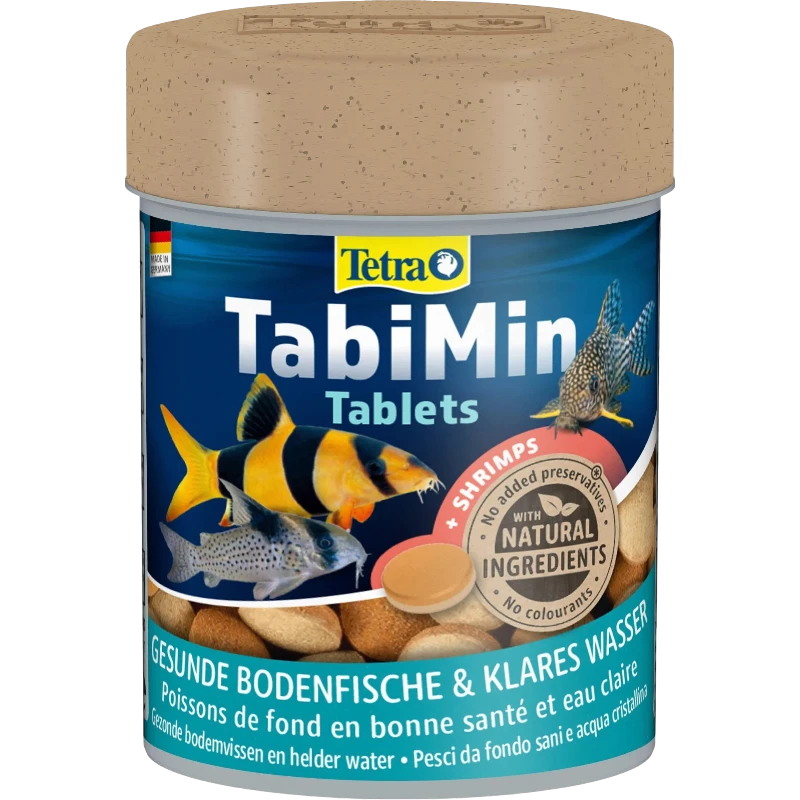 Contenitore blu scuro con compresse TabiMin di Tetra per pesci d'ornamento, con tre pesci di fondo: lo scazzone a strisce gialle e nere, il siluro maculato e il pesce screziato. In primo piano, compresse di mangime marroni, di cui una in risalto.