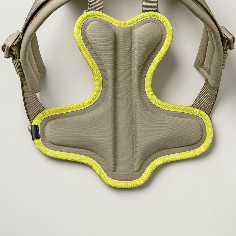 Close-up of the ergonomic back section of a grey-green dog harness with a light yellow trim. The padded EVA back pad features an integrated spinal channel to relieve pressure on the spine and heat-sealed seams.