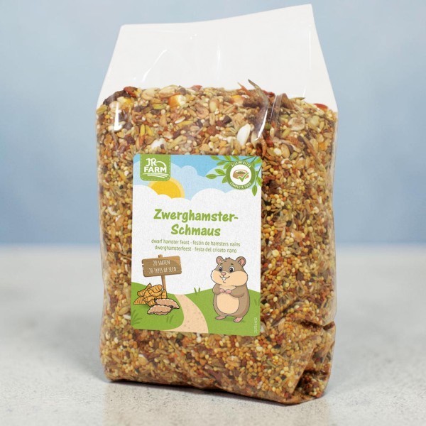 Transparent bag of dwarf hamster food, filled with a mixture of seeds, grains and dried pieces. Label: ‘JR Farm Dwarf Hamster Treat’, with the words ‘28 varieties’ and a hamster with vegetables.