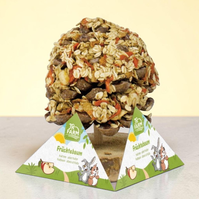 Kegelförmiger, essbarer Leckerbissen für Kleintiere, ähnlich einem kleinen Baum. Die Oberfläche ist dicht mit Haferflocken, getrockneten orangefarbenen Fruchtstücken und dunklen Körnchen bedeckt. Auf Pappständer.