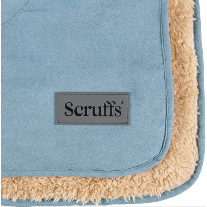 Détail d'une couverture pour chien bleu clair «Scruffs» avec doublure beige et étiquette logo.