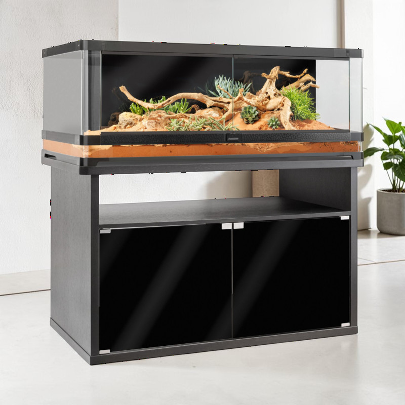 Meuble bas « Exo Terra Vista 120 » noir posé sur un sol clair. Ce meuble robuste, doté de deux portes brillantes, accueille un terrarium panoramique avec un substrat sableux, des plantes succulentes et du bois flotté, créant ainsi un paysage désertique.