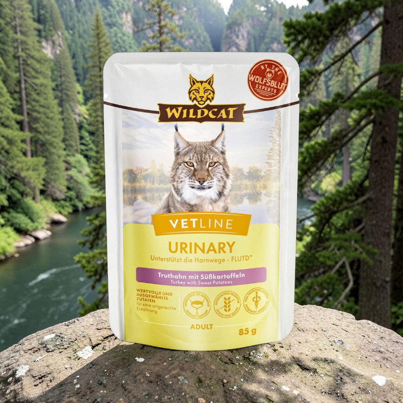 White and yellow stand-up pouch featuring ‘ Wildcat ’ Vetline Urinary cat food, turkey with sweet potatoes, set against a rocky backdrop. The packaging depicts a lynx against a river landscape. Supports urinary health, grain-free, 85g net weight.