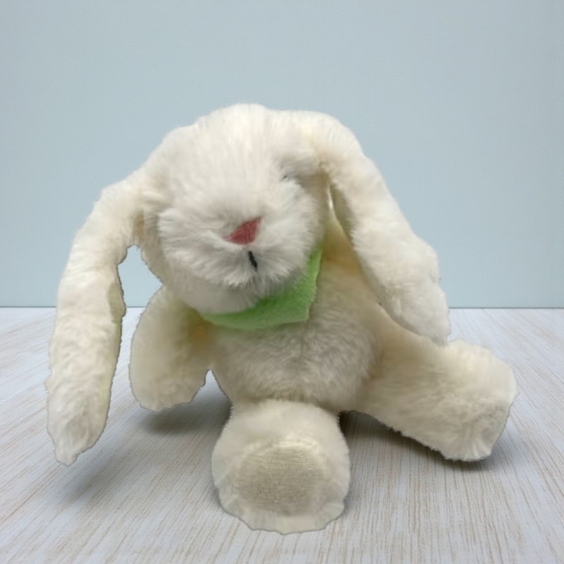 Ein cremefarbener Stoffhase "Harry Hoppelhase" mit grünem Tuch sitzt auf einem hellen Untergrund.