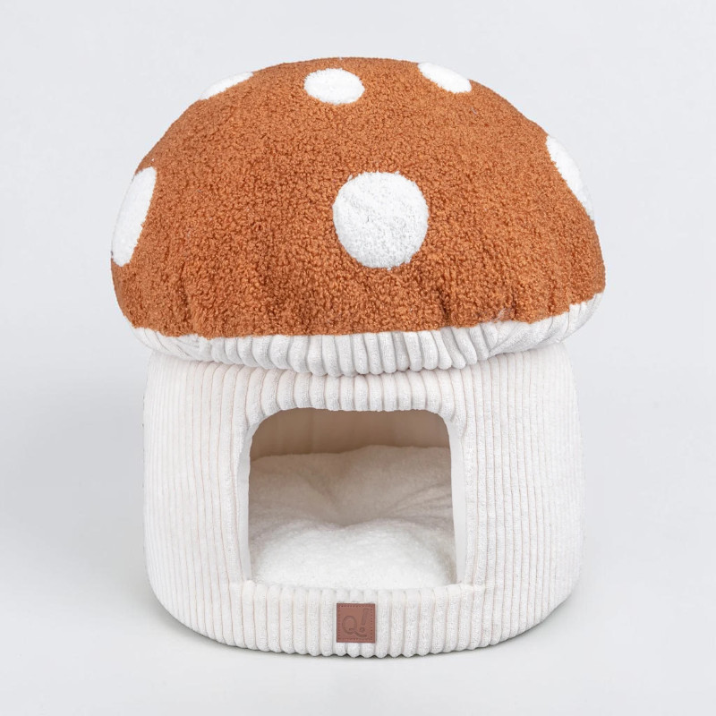 Cosy mushroom-shaped cat bed with a fluffy brown cap featuring large white dots. The light beige, ribbed stem has a rectangular opening at the front leading to the soft, white plush cushion inside – ideal for relaxing.
