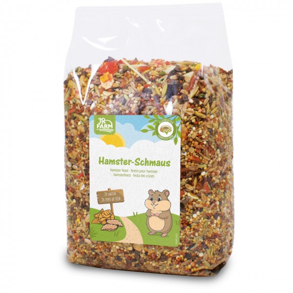 A clear plastic bag containing JR Farm Hamster Treats, a colourful mix of 20 seeds, grains and dried fruits. The label features a smiling cartoon hamster and the words ‘Hamster Treats’ with ‘Complete Food’.