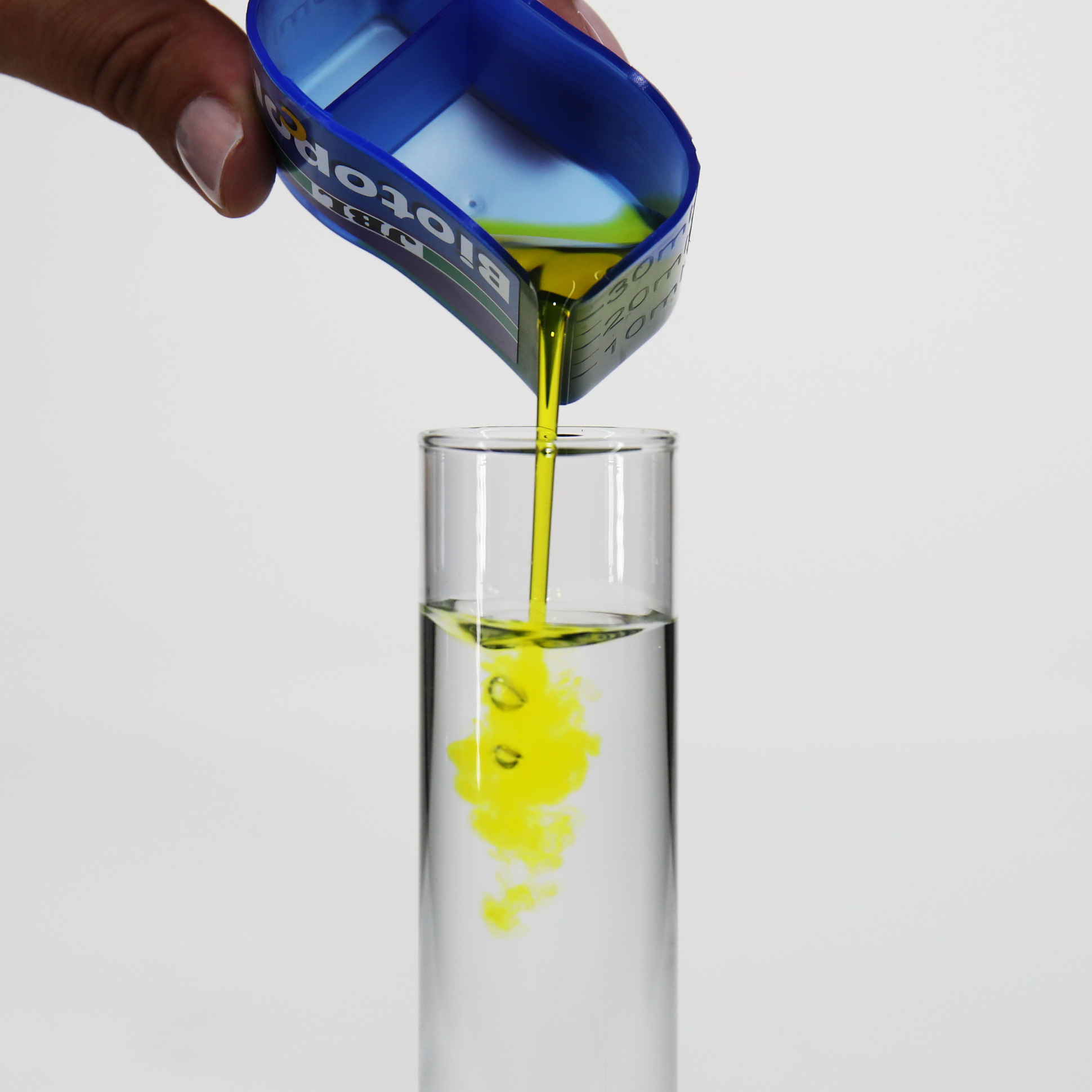 Yellow JBL Biotopol C liquid is poured into a glass tube with water.