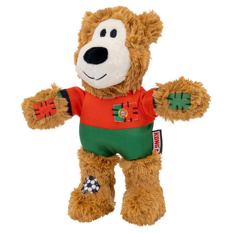 Morbido giocattolo per cani marrone a forma di orso o leone, con maglia rosso-verde. Sul petto è presente una toppa con la bandiera portoghese. Le braccia e una gamba presentano toppe decorative, tra cui un motivo calcistico. Etichetta Kong visibile.